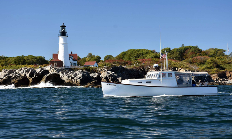 Boat cruising by Portland Head Light. Photo Provided by Casco Bay Custom Charters