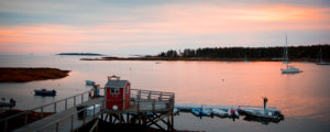 Couple on dock, sunset over waterfront. Photo Credit: Russell Caron Wedding Photography