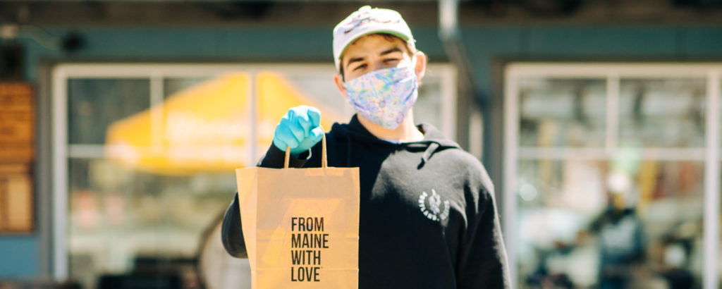 Man in mask and gloves holding bag saying 'from Maine with love', Photo Courtesy of Mat Trogner, via Allagash Brewing Man in mask and gloves holding bag saying 'from Maine with love', Photo Courtesy of Mat Trogner, via Allagash Brewing