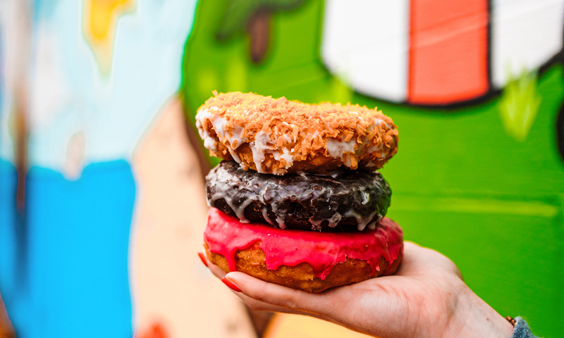 Donuts in front of mural. Photo Provided by The Holy Donut