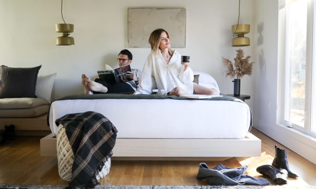 Guests lounging in bed inside a cabin studio at AWOL Kennebunkport in Kennebunkport. Photo Credit: Maiike Bernstrom