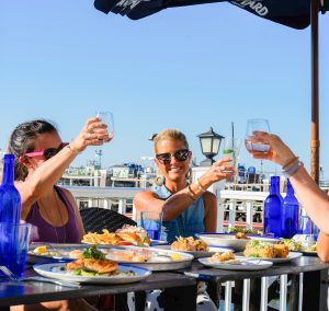 Group of people cheering drinks on deck, Photo Credits: Saltwater Grille