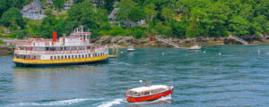 Boat in Casco Bay near island next to yellow ferry; Photo Credit: Peter G. Morneau Photography