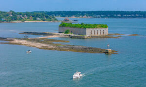 Boat sailing past rocky Fort Gorges on blue water; Photo Credit: Peter G. Morneau Photography