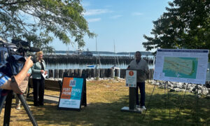 Person a giving press conference near boat marina and harbor; Photo Credit: Angie Helton