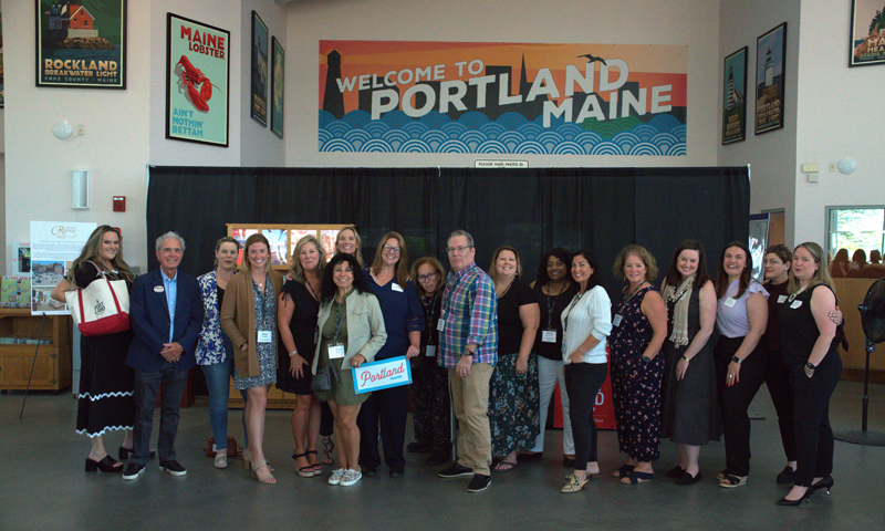 Group posing in front of 'Welcome to Maine' sign; Photo Credit: Digital Edge
