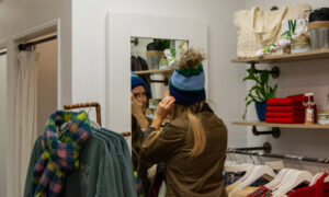 Woman trying on hat in Freeport store; Photo Credit: Lauren Witt at Visit Portland